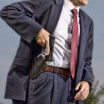 man in suit pulling his gun out of the holster